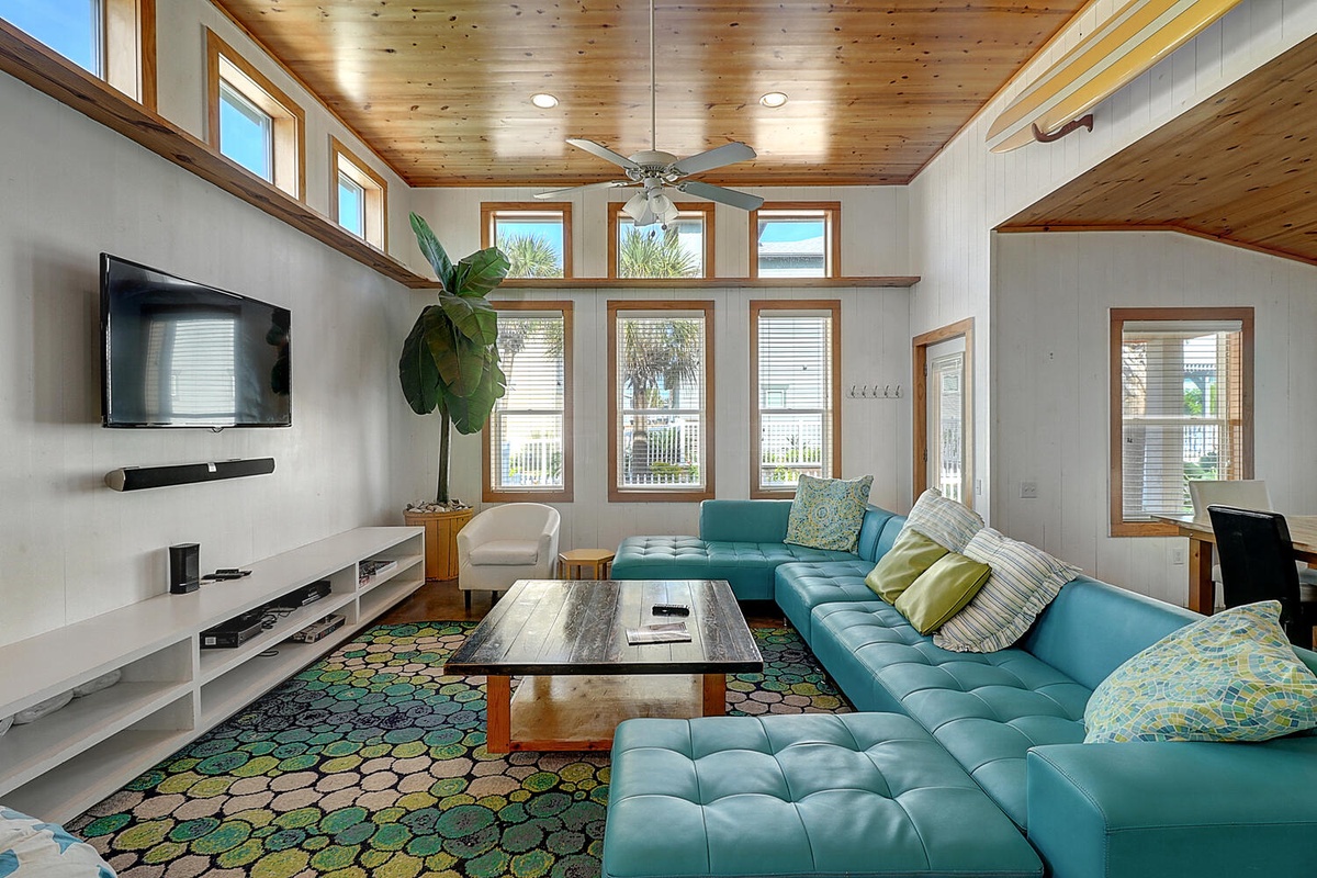 Relax in your modern living space with soaring wood ceilings, turquoise sectional, and abundance of natural light streaming through floor-to-ceiling windows.