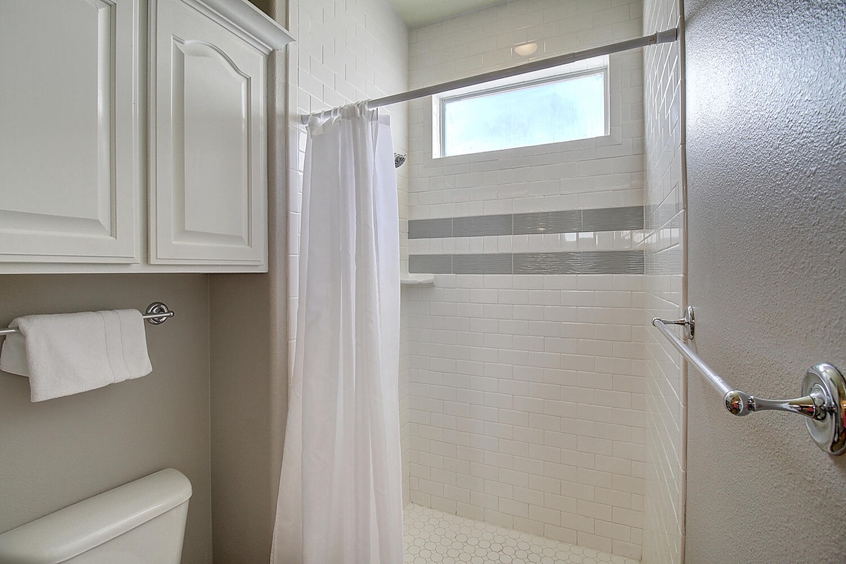 Step into your pristine bathroom featuring gleaming subway tile and a spacious walk-in shower with natural light.