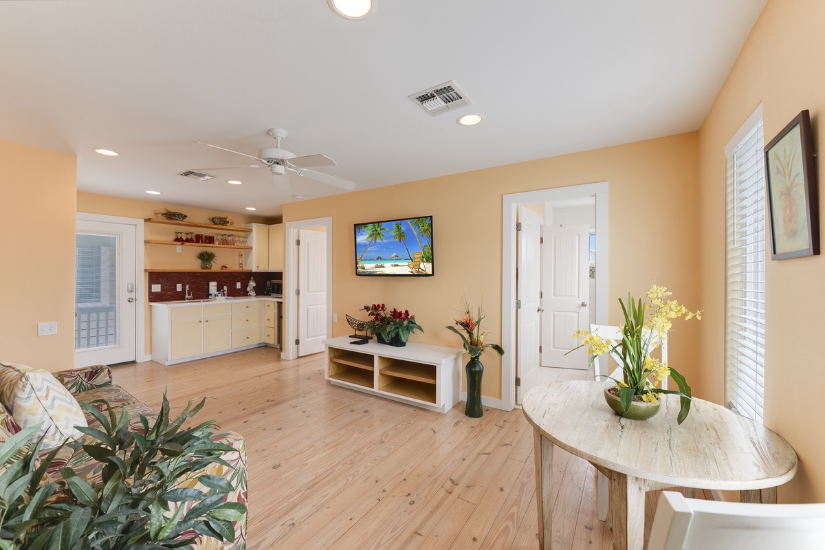 Relax in your bright, tropical-themed living space with warm wood floors, a fully equipped kitchenette, and cheerful coastal decor.