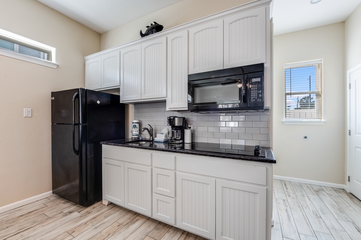 Your fully equipped kitchen features sleek black appliances, granite counters, and bright subway tile backsplash perfect for cooking memorable meals.