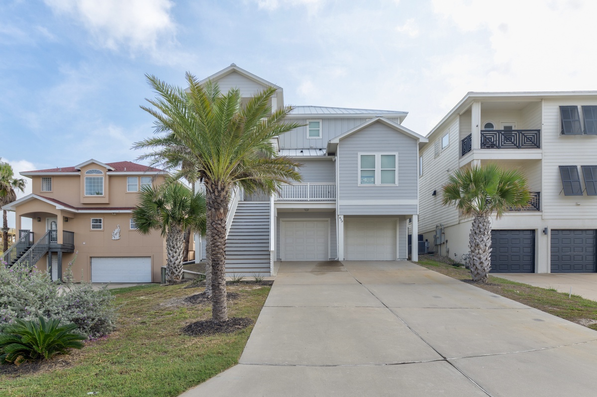 Coastal neighborhood featuring beach houses with palm trees and modern architecture in a sunny residential setting.