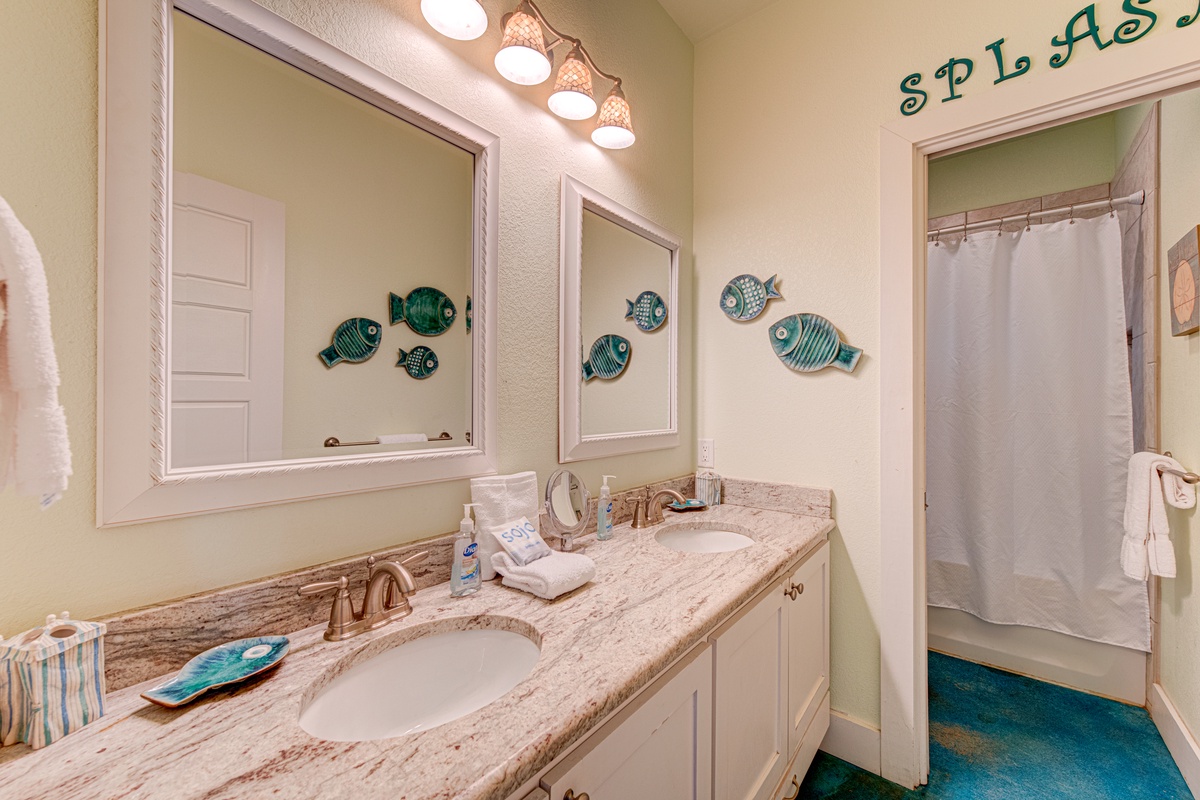Dive into your coastal-themed bathroom featuring elegant granite counters, whimsical fish art, and everything you need to refresh after your beach adventures.