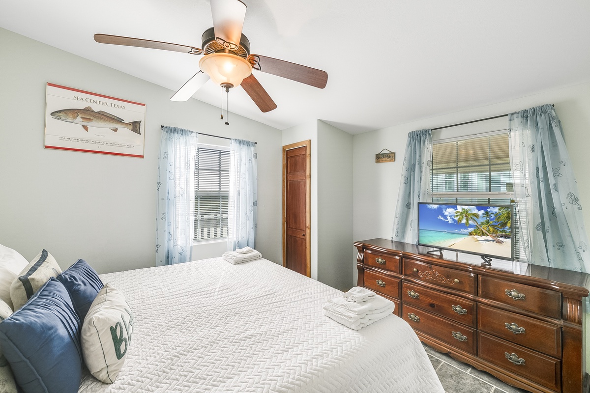 Drift off in this coastal-themed bedroom with crisp linens, gentle ceiling fan, and charming nautical touches throughout.