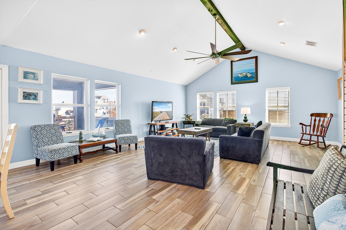 Relax in your bright, coastal-inspired living room with vaulted ceilings, comfortable seating, and natural light streaming through multiple windows.
