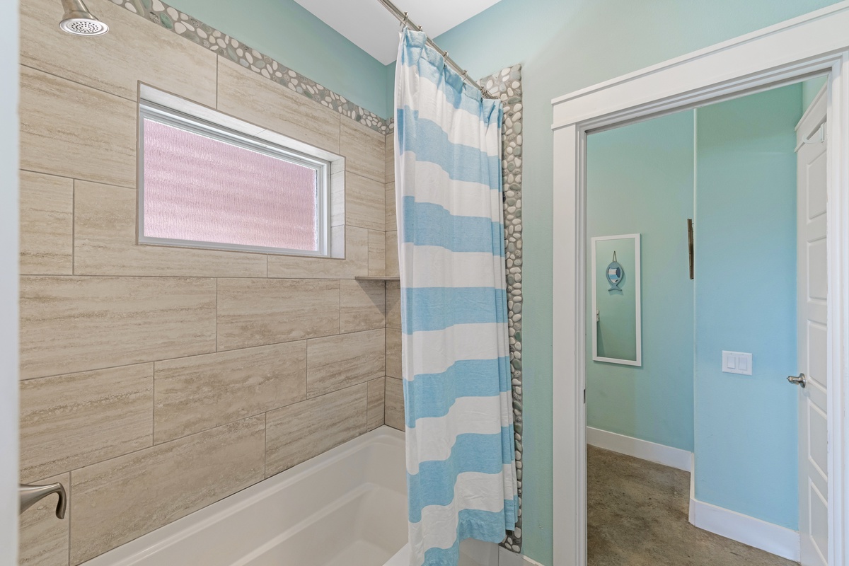 Freshen up in the tub and shower combination, accented with coastal colors and charming pebble-style tile details.