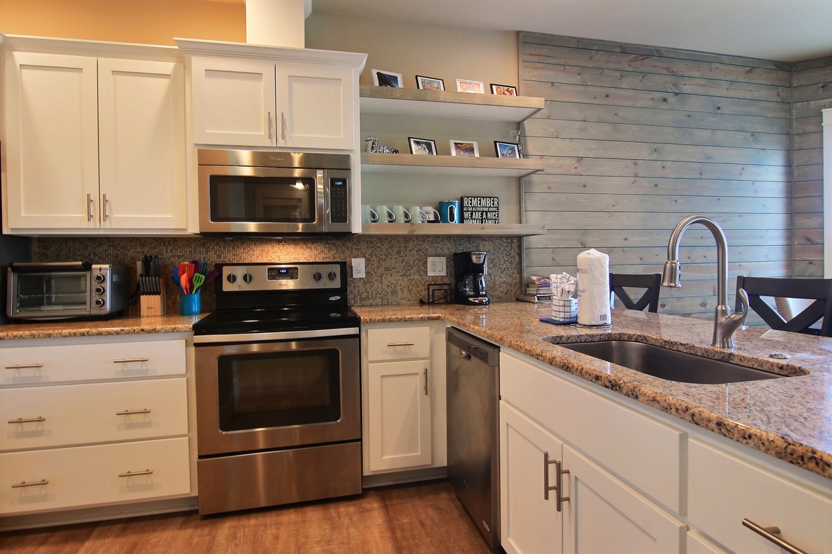 Your spacious kitchen features granite counters, stainless appliances, and rustic shiplap walls for memorable home-cooked meals together.