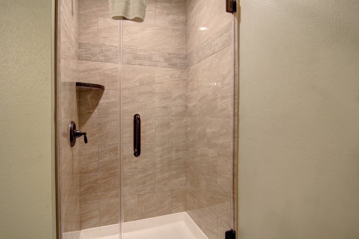 Step into your private glass-enclosed shower with elegant stone walls and modern fixtures for a refreshing start to your day.
