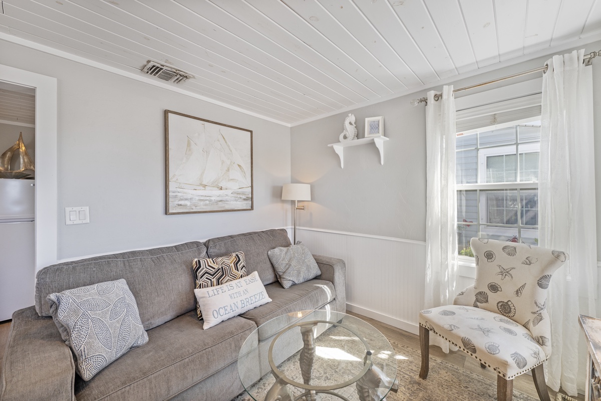 Sink into this cozy living room where coastal charm meets comfort. Your mornings begin with coffee on plush seating beneath beautiful exposed beams.