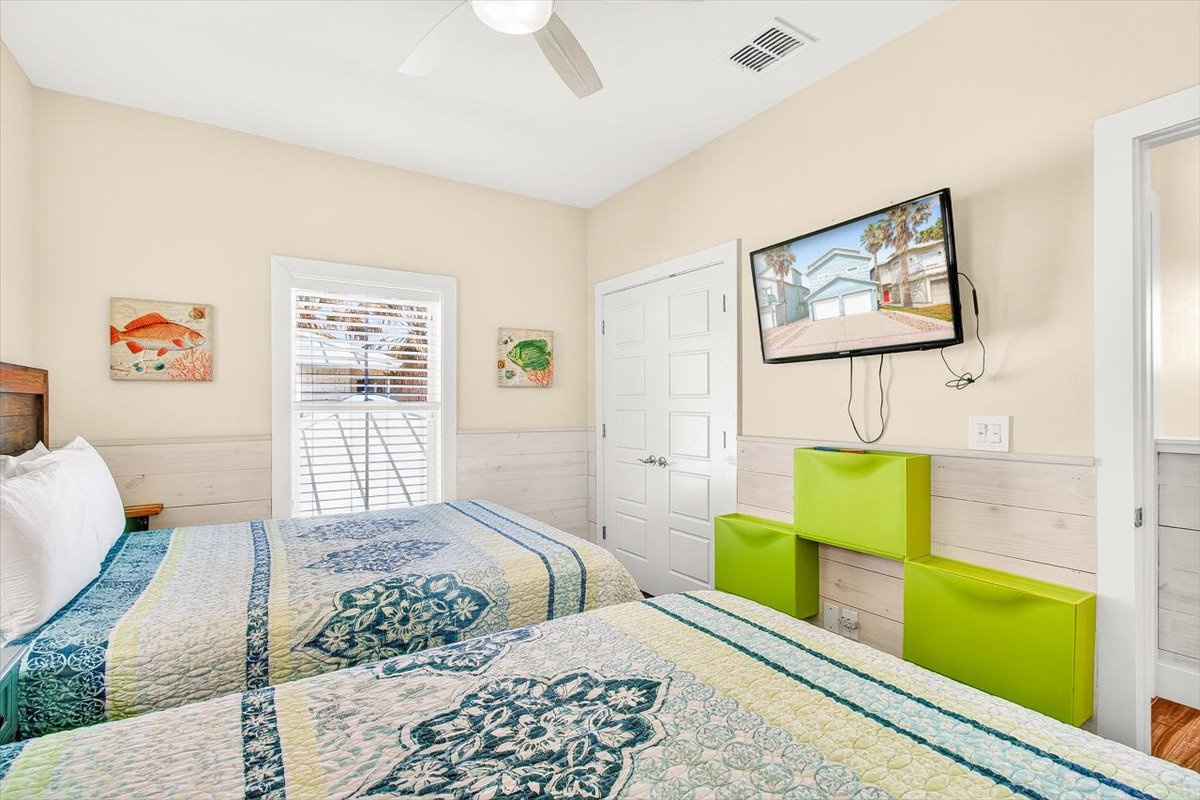 Unwind in your bright bedroom with beach-themed art, cozy bedding, and entertainment ready for peaceful evenings.