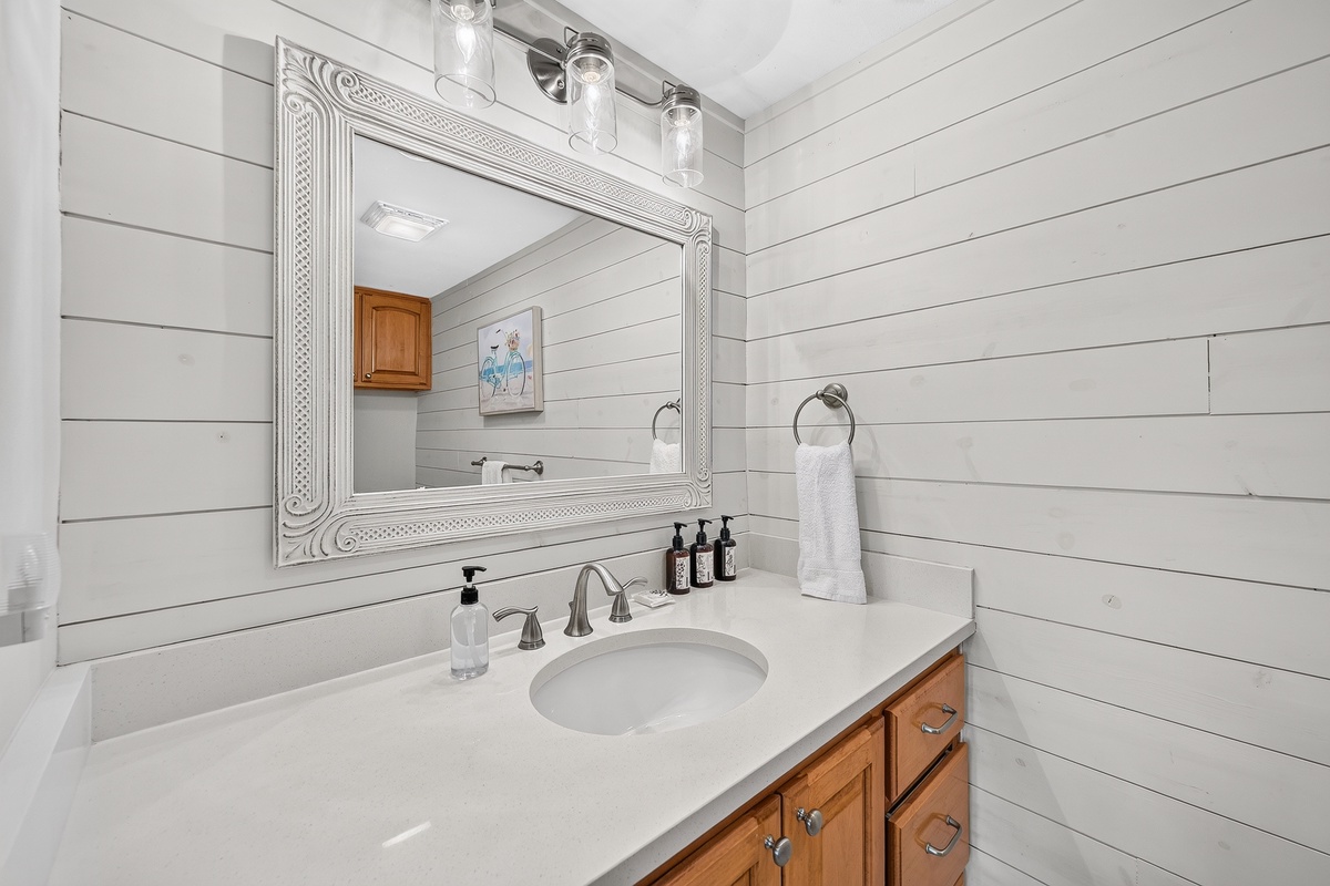 Freshen up in your stylish bathroom with shiplap walls, elegant white countertops, and a decorative framed mirror. Clean towels and premium toiletries are ready for your arrival.
