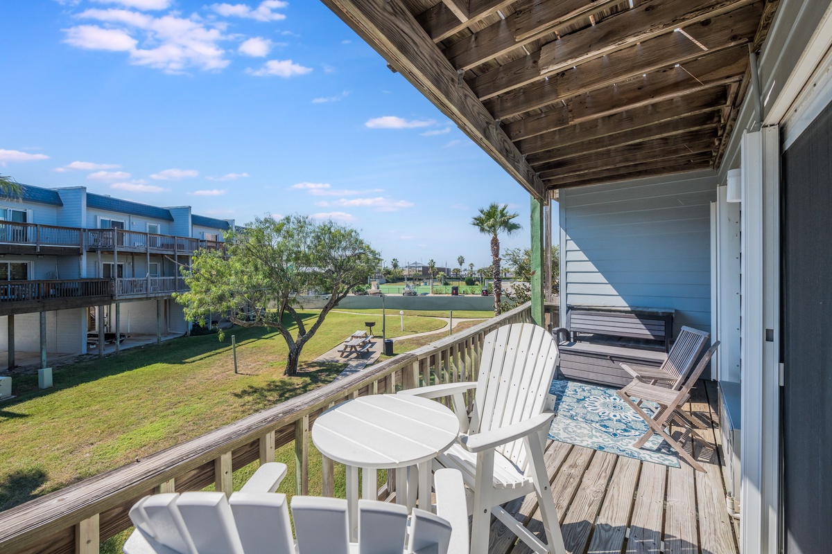 Step onto your private balcony where white Adirondack chairs invite you to relax with morning coffee while enjoying peaceful garden views.