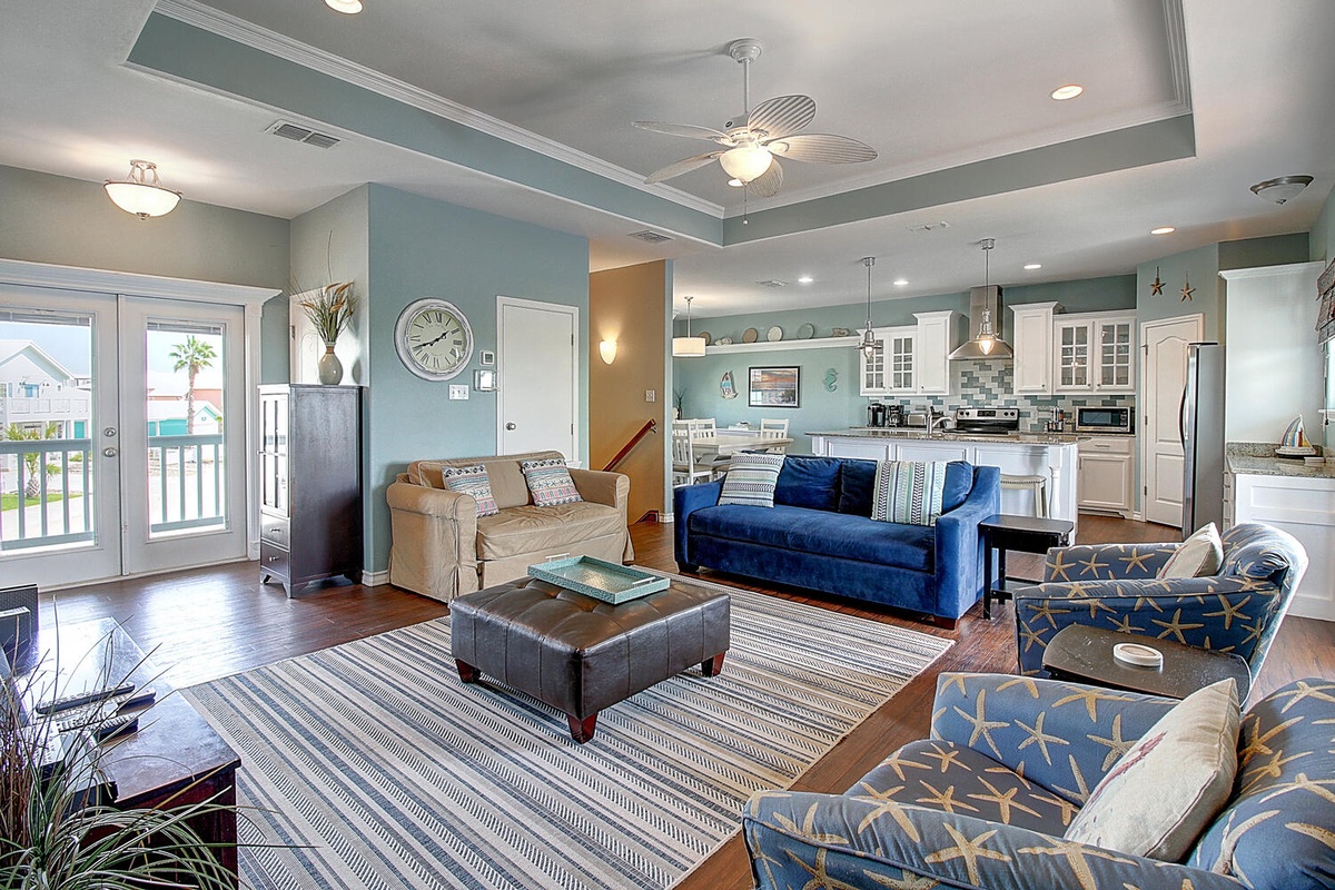 Relax in your spacious open-concept living area with coastal blues, comfortable seating, and modern kitchen access.