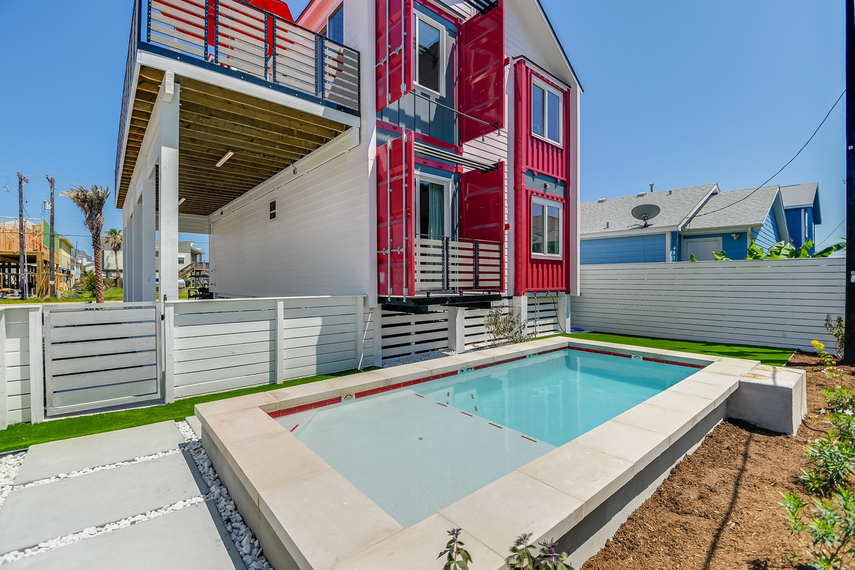 Modern beachside property features a vibrant red and white exterior with private pool in a contemporary coastal neighborhood.