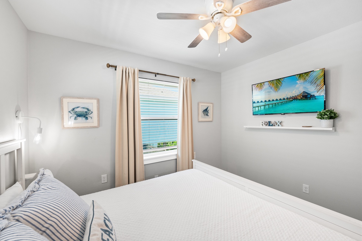 Rest easy in your serene bedroom with fresh linens, a gentle ceiling fan, and coastal touches that bring calm and comfort to your retreat.