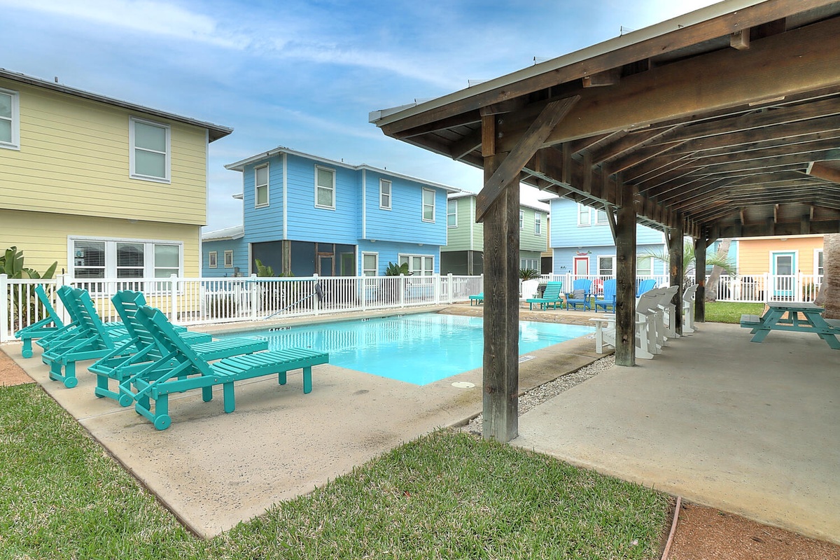 Dive into your private pool surrounded by colorful beach houses, then relax on teal loungers under the shaded pavilion.