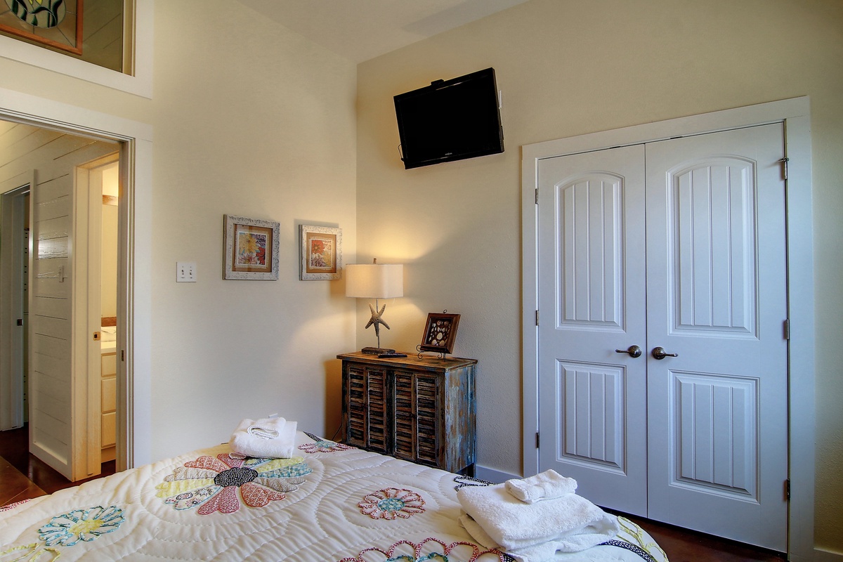 Your cozy bedroom features cheerful quilted bedding, warm lighting, and thoughtful touches like artwork and a mounted TV for your comfort.
