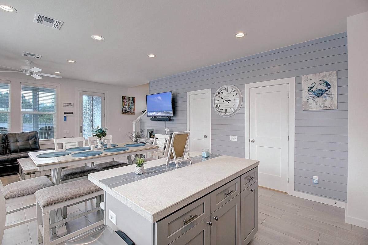 Your open-concept kitchen flows seamlessly into the dining area, where coastal decor and modern amenities create the perfect gathering space for meals.