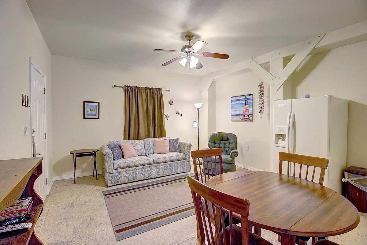 Your spacious living area combines comfort and functionality with a cozy sofa, dining table, and charming coastal touches throughout.