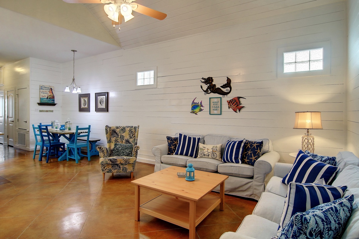 Sink into plush sofas with nautical pillows in your coastal-themed living room, where whimsical sea creatures dance across shiplap walls.