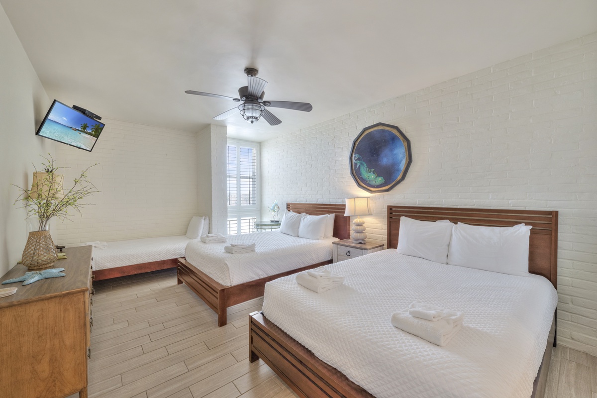 Rest comfortably in your spacious bedroom featuring two queen beds, modern amenities, and coastal artwork that creates a serene atmosphere.
