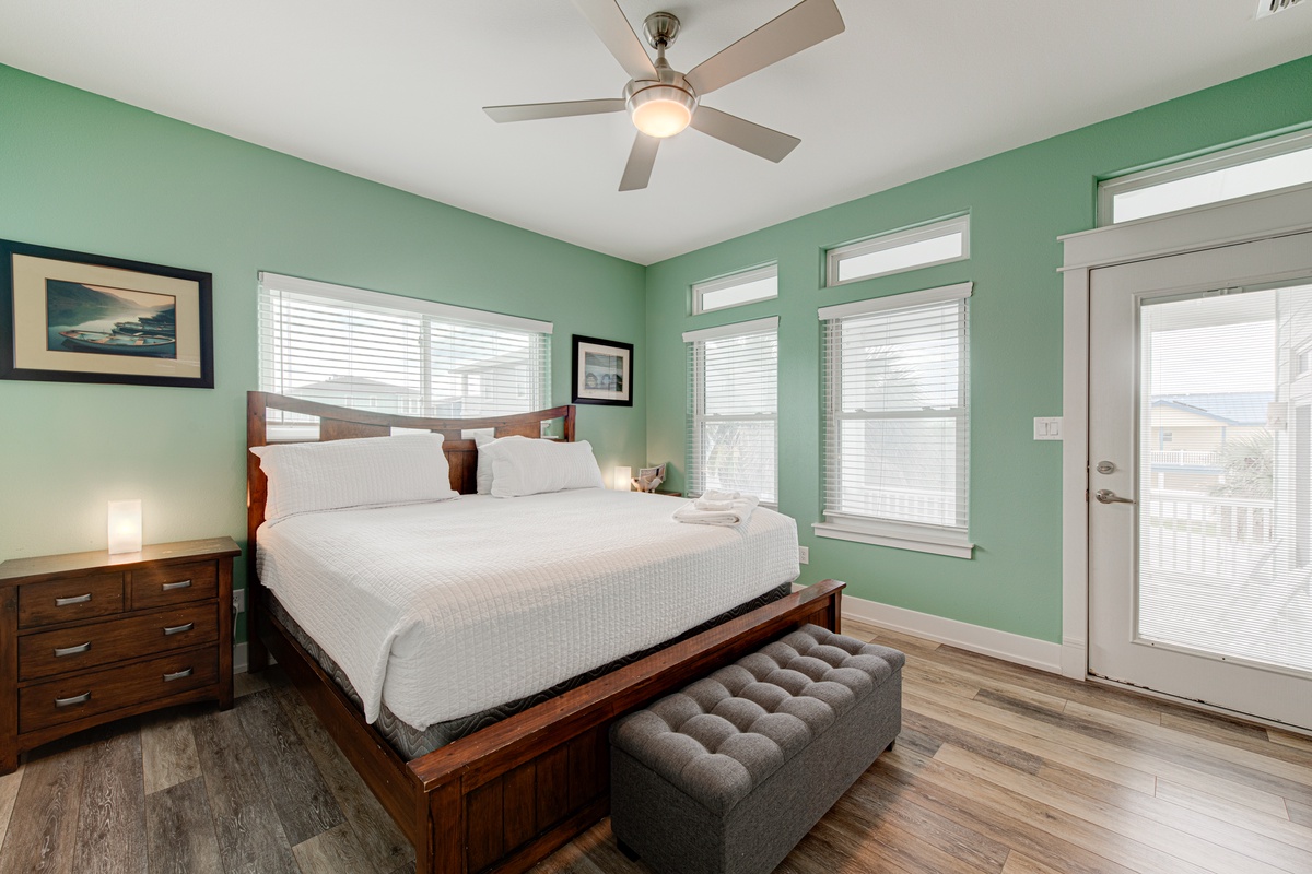 Unwind in your serene bedroom with soothing green walls, crisp white linens, and gentle ceiling fan creating the perfect retreat.