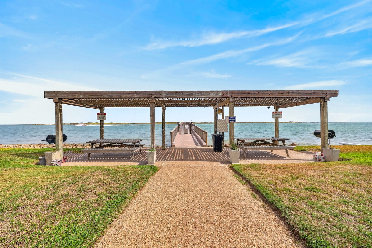 A shaded waterfront pavilion and dock offer peaceful waterside gathering spots in the surrounding area. Perfect for outdoor picnics, with direct access to the calm bay waters beyond.