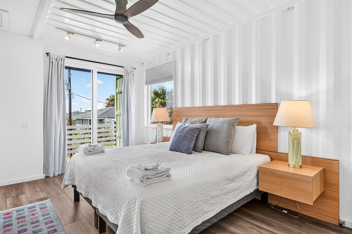 Step into your serene primary retreat where crisp white walls and warm wood tones create a calming oasis in your king bed. Fresh towels await your arrival, and the ceiling fan ensures your comfort year-round.