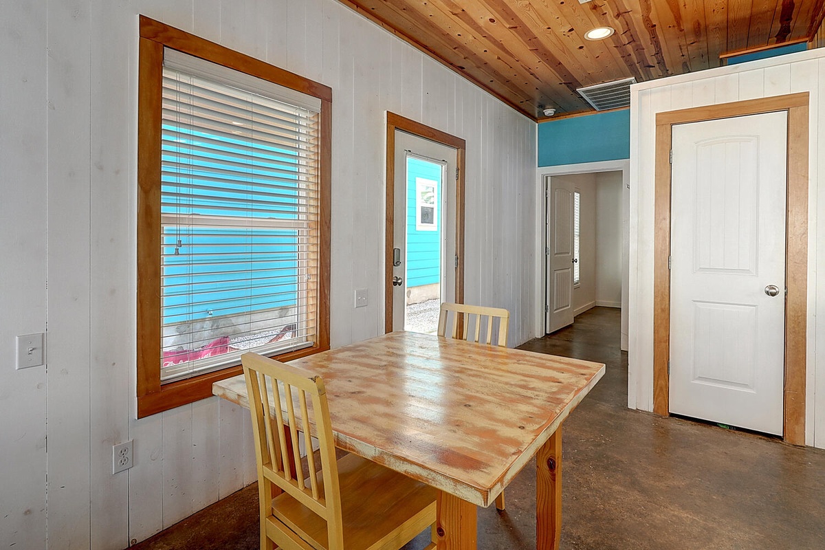 Gather around your rustic wooden dining table beneath beautiful cedar ceilings, with natural light streaming through warm wood-framed windows.