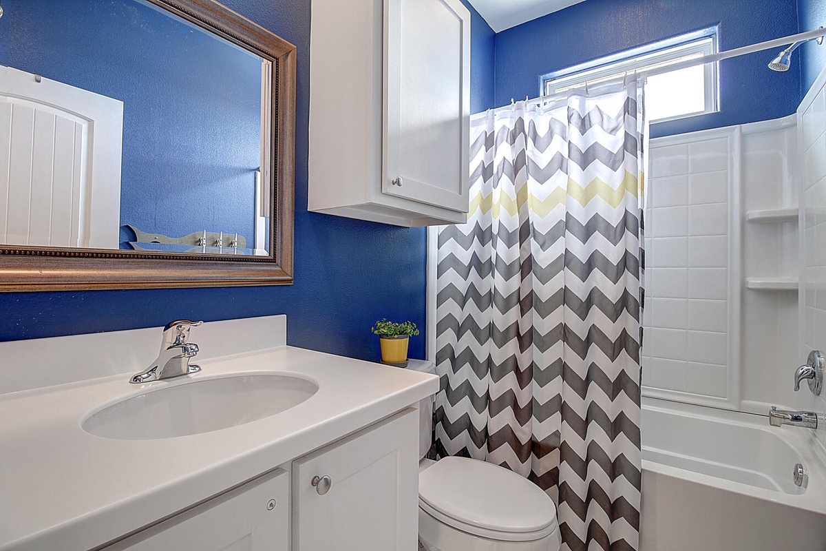 Freshen up in your vibrant blue bathroom featuring a stylish chevron shower curtain and modern amenities for your comfort.