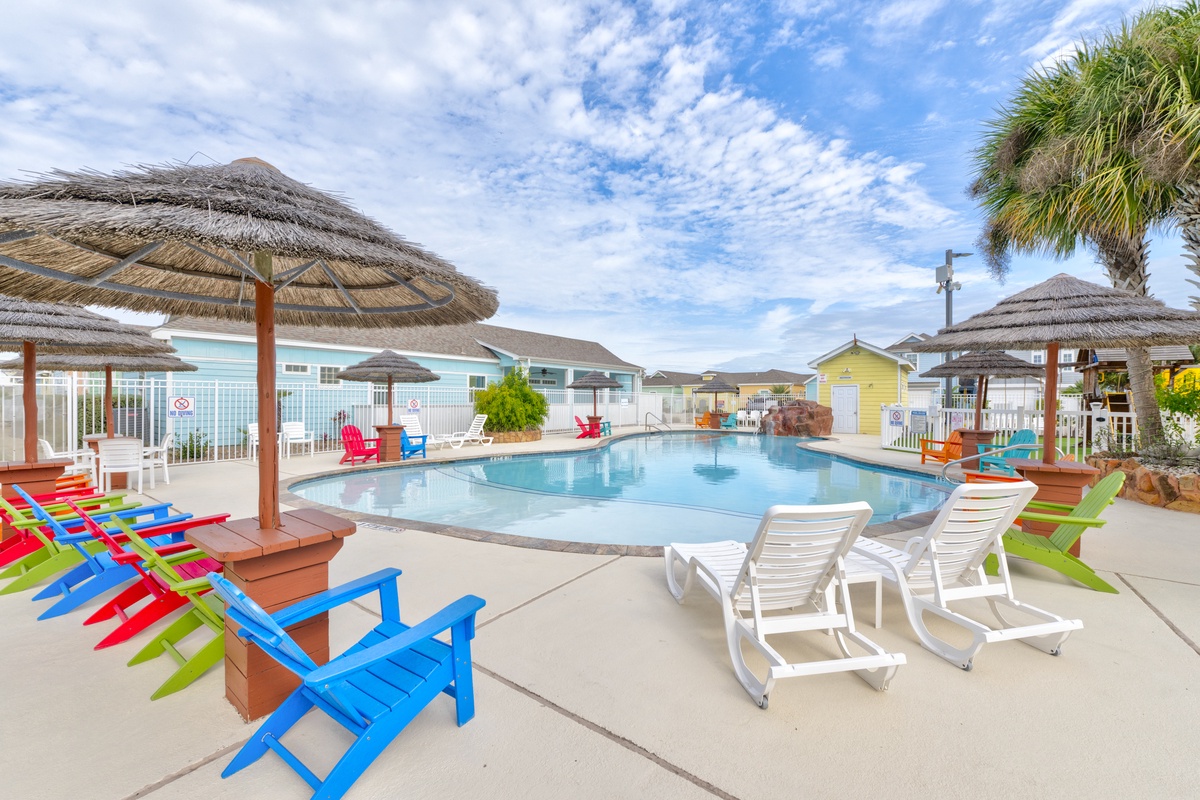 Soak up the sun poolside with colorful beach chairs and thatched umbrellas creating your perfect tropical oasis.