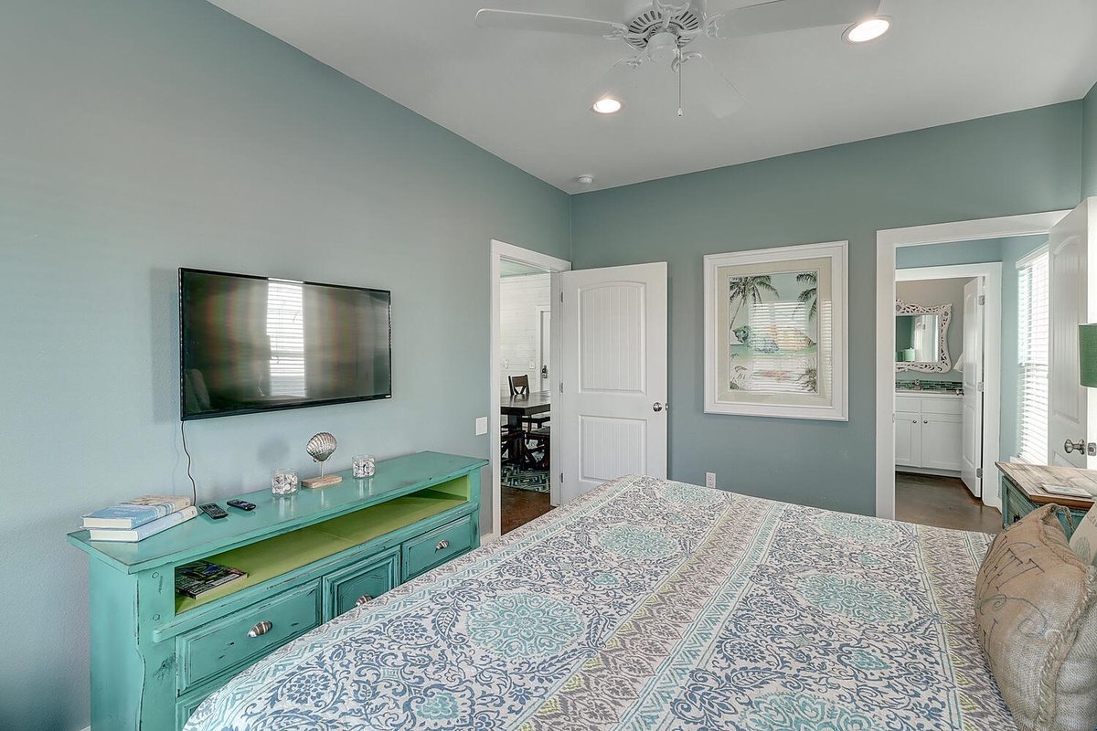 Your coastal-inspired bedroom features soothing seafoam walls, elegant furnishings, and modern amenities for a perfect seaside retreat.
