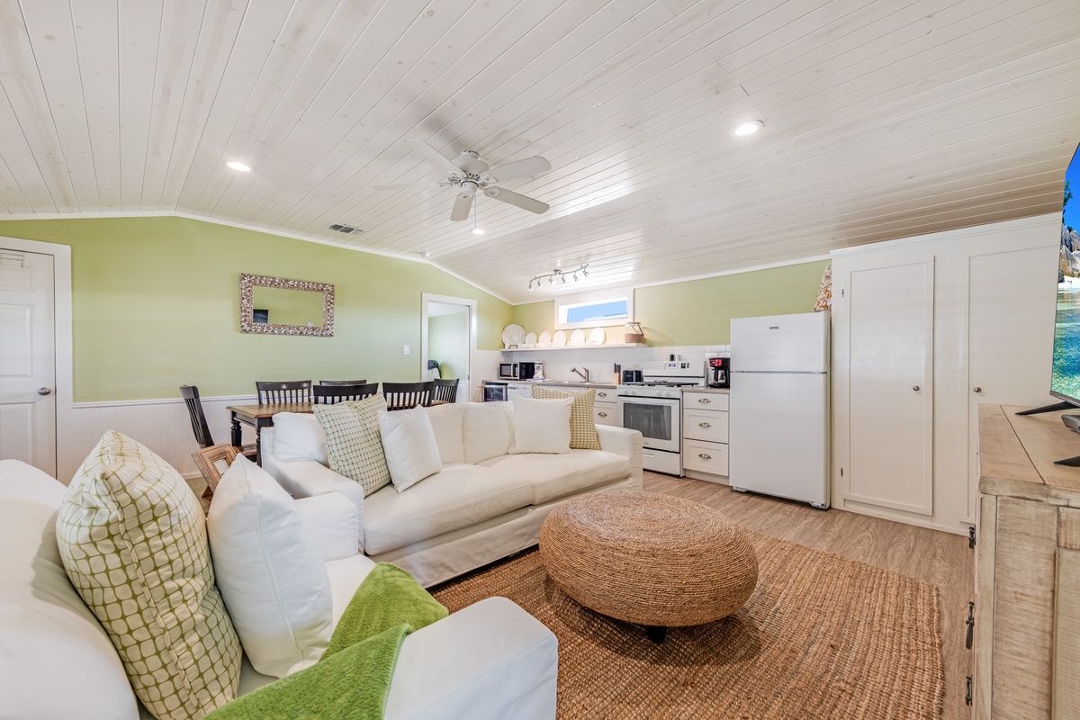Relax in this bright open-concept living space where coastal charm meets comfort, featuring a fully equipped kitchen and cozy seating area.
