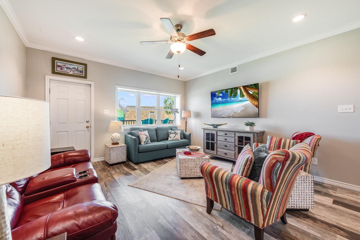Relax in your comfortable living space with plush seating, large TV, and ceiling fan keeping you cool.
