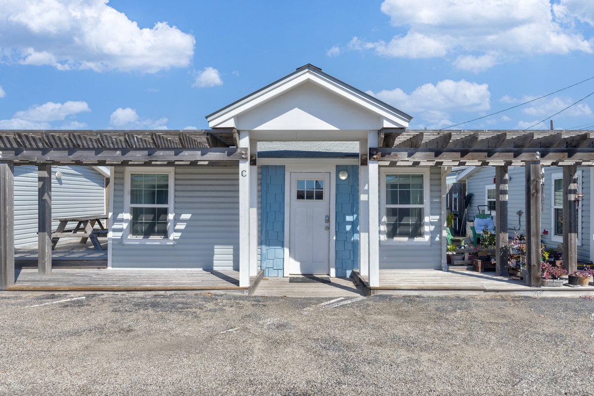 Charming coastal cottage with blue accents and covered porch, perfectly positioned for your seaside getaway.