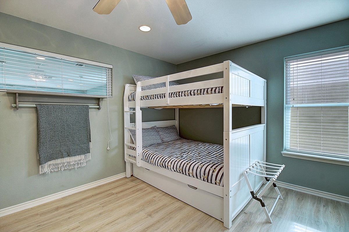 Your comfortable bunk bedroom features crisp linens and peaceful green walls, perfect for restful nights with natural light filtering through.