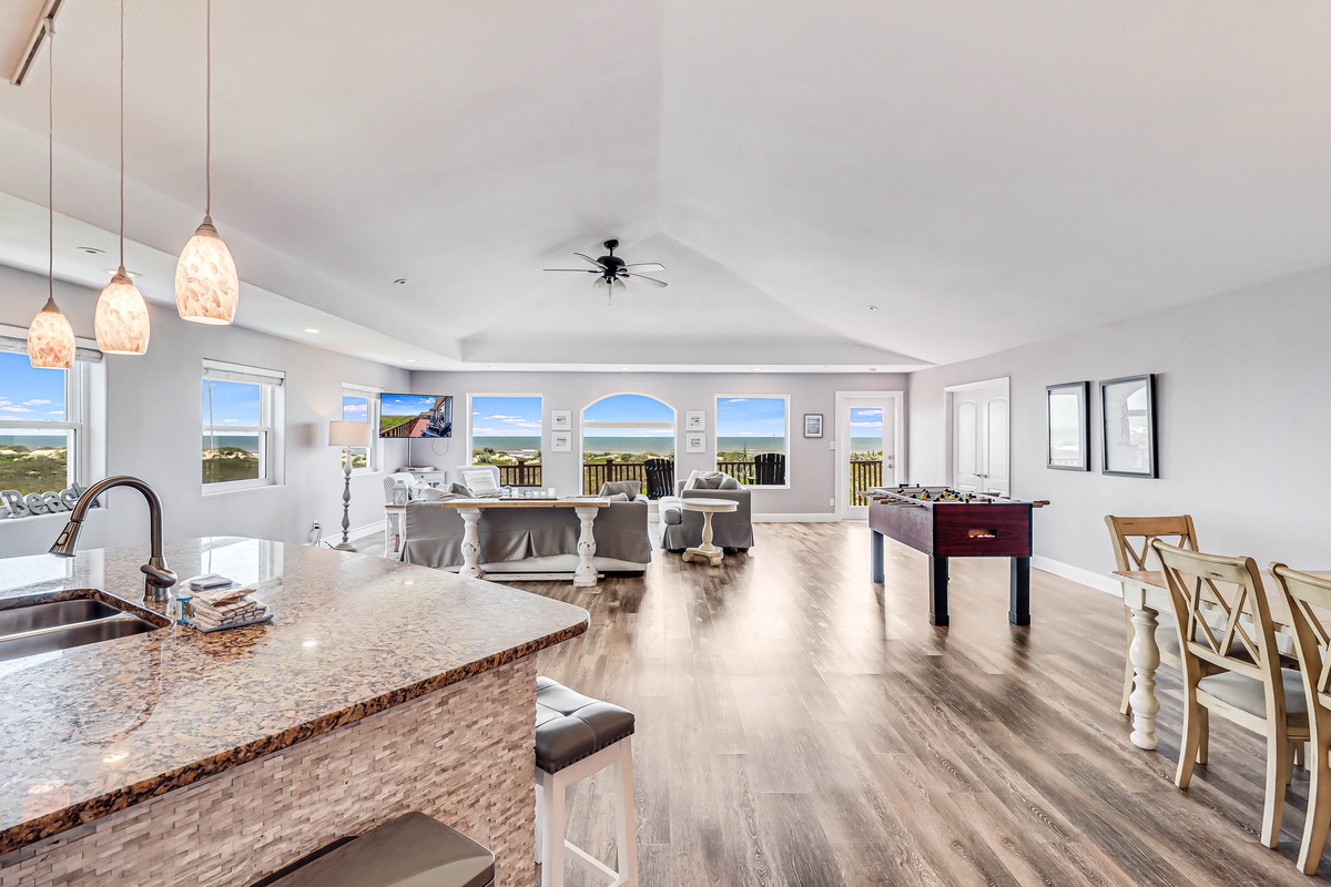 Your open-plan living space flows seamlessly from kitchen to lounge, with gleaming floors and stunning panoramic views through every window.