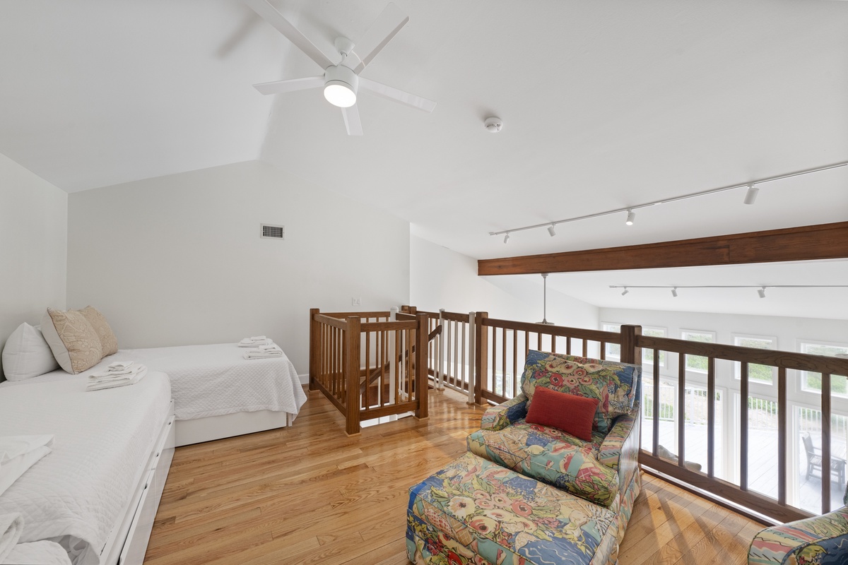 Relax in your bright loft bedroom with vaulted ceilings, cooling fan, and cozy reading nook overlooking the living space below.