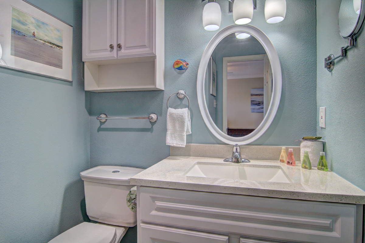 Refresh in your beautifully appointed bathroom featuring soothing sea-glass walls, elegant white cabinetry, and thoughtful amenities for your comfort.