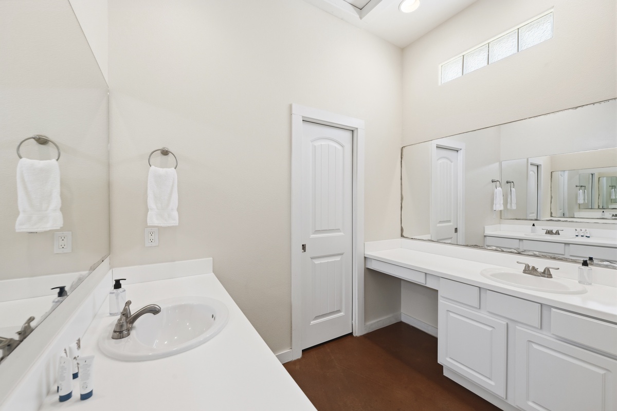 Freshen up in your spacious dual-vanity bathroom, where natural light from above and crisp white finishes create a bright, welcoming space for your morning routine.