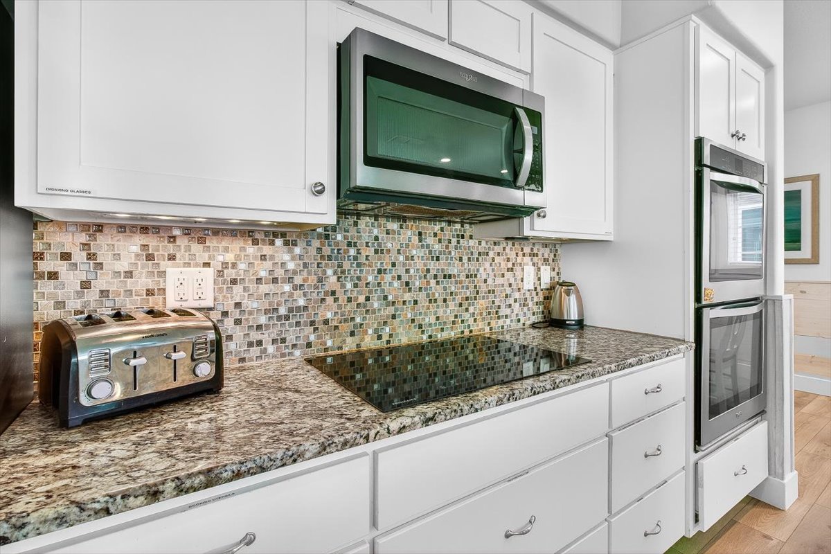 Your fully equipped kitchen features granite countertops, mosaic tile backsplash, and modern appliances for creating memorable meals.