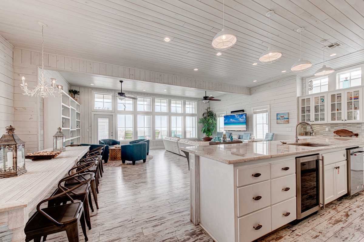 Gather with loved ones in this stunning coastal kitchen featuring marble countertops, farmhouse charm, and open living perfect for memorable meals together.