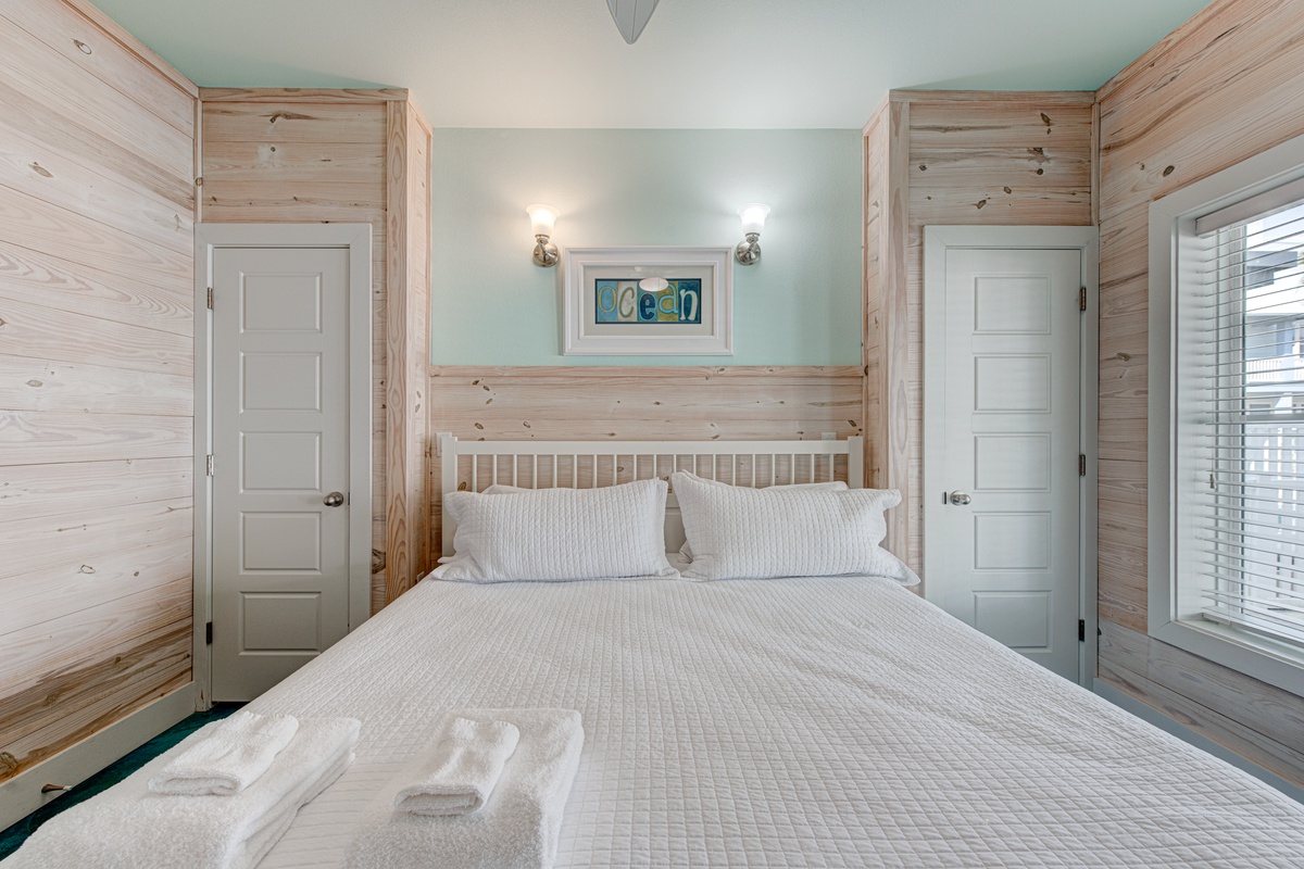 Your coastal bedroom awaits with crisp linens, charming wood accents, and soothing sea-foam walls that whisper ocean dreams.