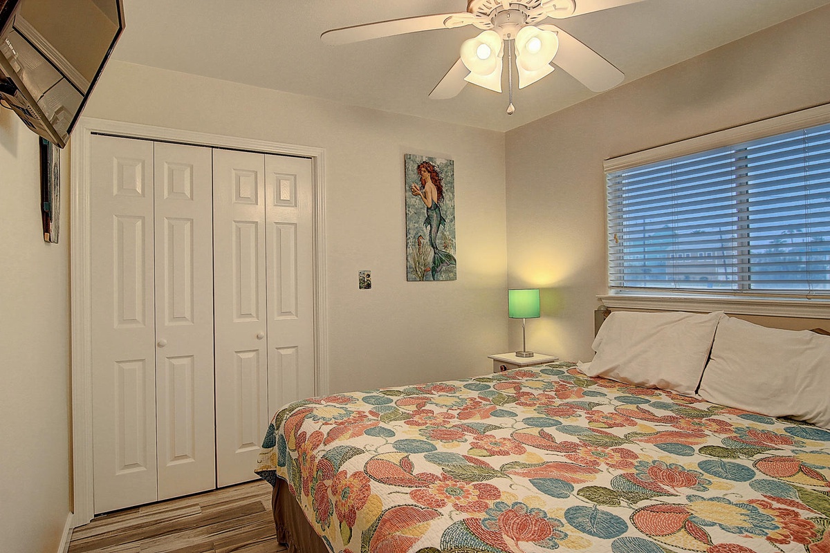 Your cozy bedroom features a comfortable bed with colorful linens, gentle ceiling fan, and ample closet space for all your belongings.