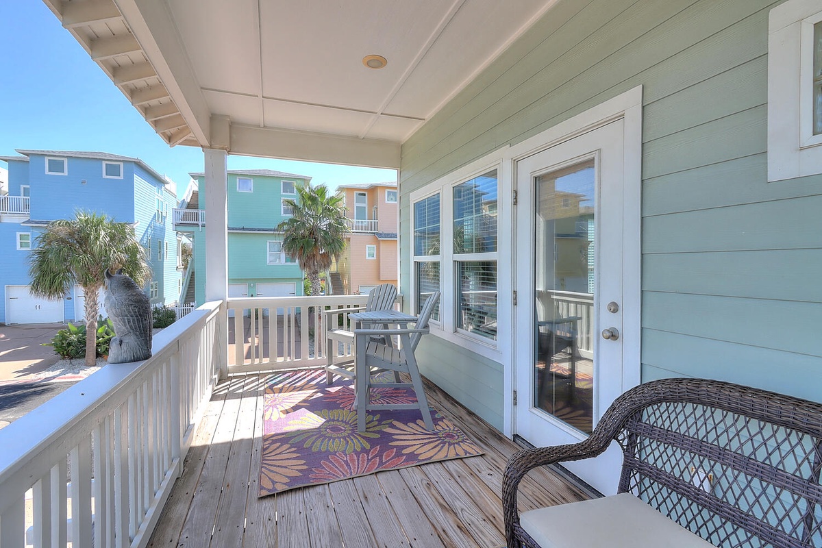 Relax on your private covered balcony with wicker seating and colorful tropical touches, overlooking charming beach houses.