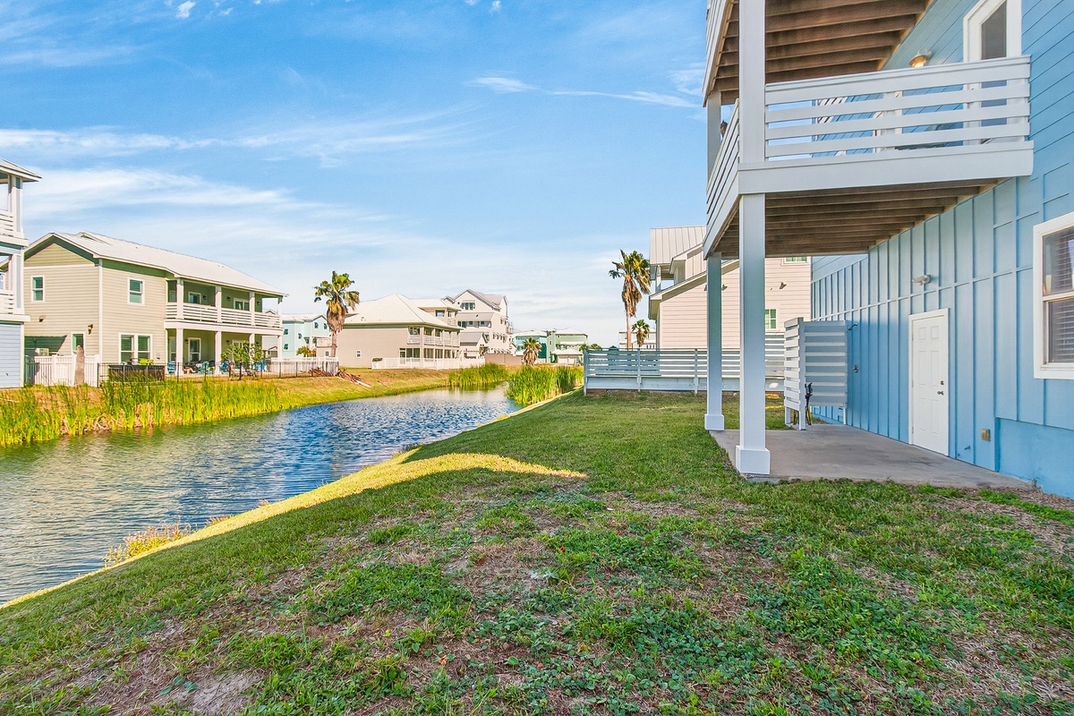 Waterfront vacation homes line a peaceful canal with covered porches and palm trees creating a tranquil coastal community atmosphere.