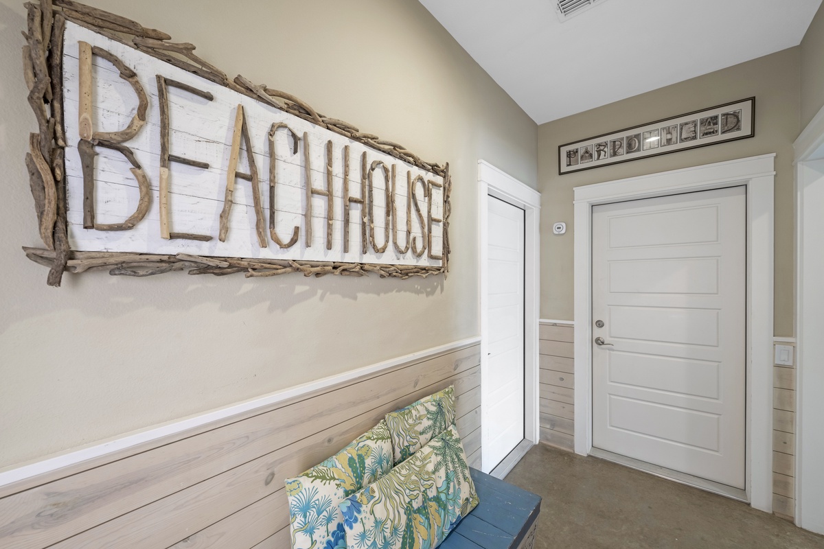 Step into your welcoming beachhouse entrance, where rustic charm meets coastal comfort with weathered wood accents and a cozy reading nook.