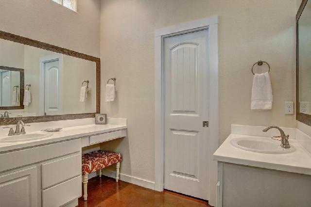 Your elegant bathroom features dual sinks, pristine white cabinetry, and warm wood floors that create a spa-like retreat for your morning routines.