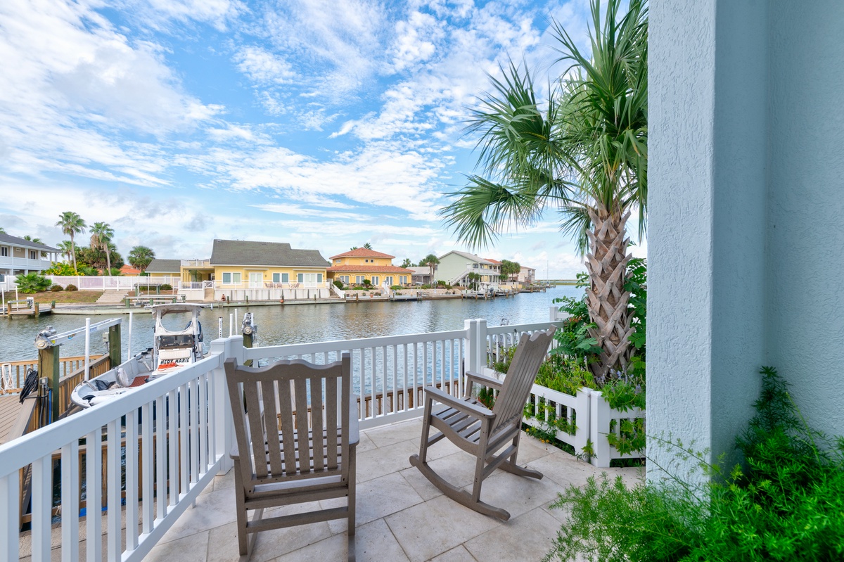 A quiet waterfront neighborhood with private boat docks and charming coastal homes across the canal, framed by palm trees and tropical greenery.