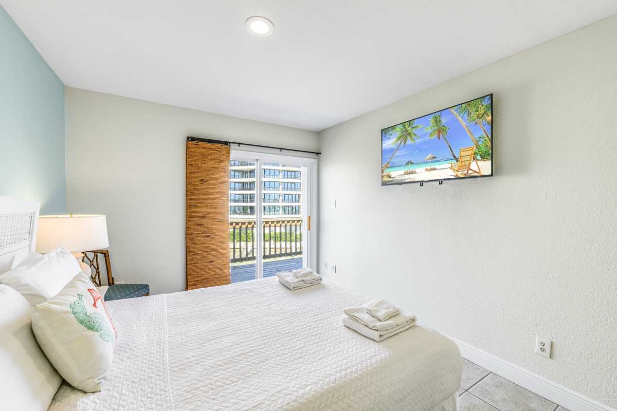 Unwind in your serene bedroom with tropical beach views on the wall-mounted TV and fresh towels waiting on your comfortable bed.