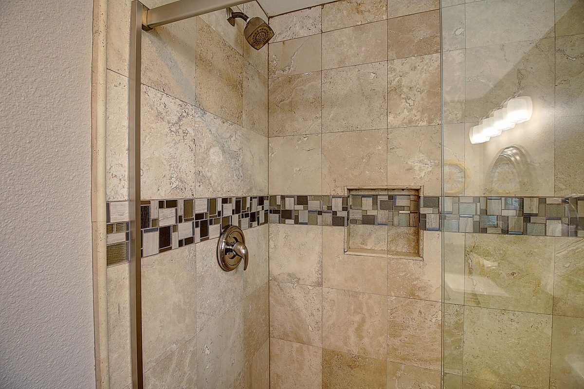 Indulge in your private spa-like shower with beautiful natural stone tiles and elegant mosaic accents for ultimate relaxation.